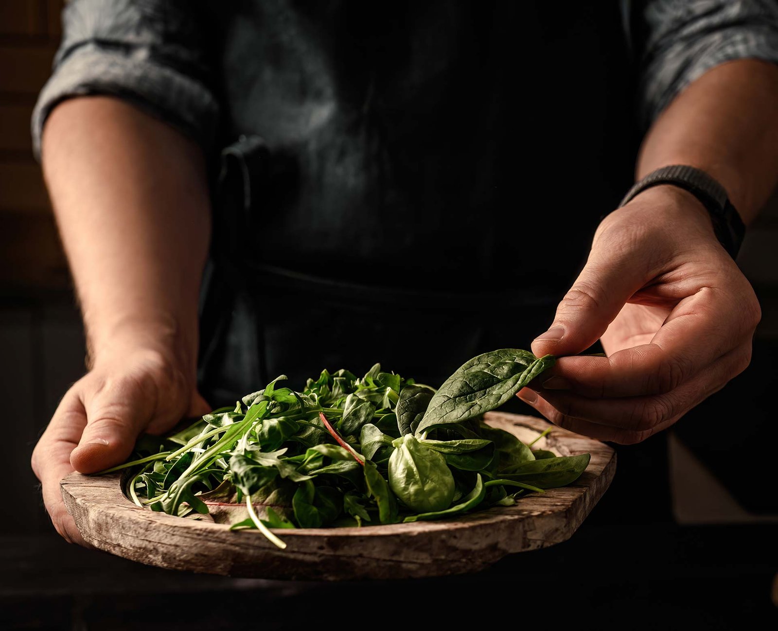 Chef holding fresh green herbs sourced from local suppliers in Cornwall